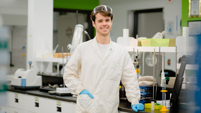 Brosnon Peters leaning on a lab counter surrounded by equipment