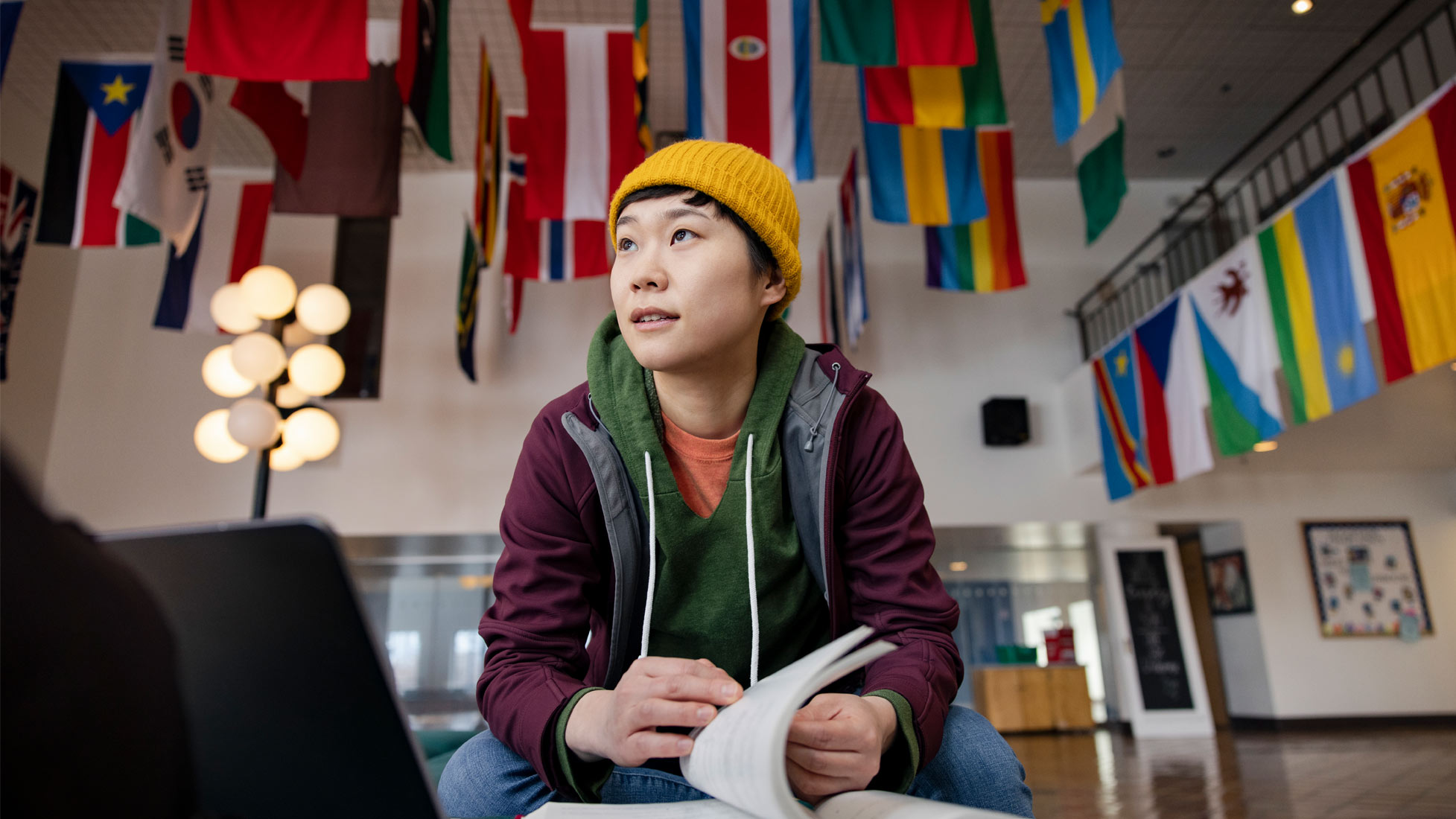 Student sitting beneath flags on campus