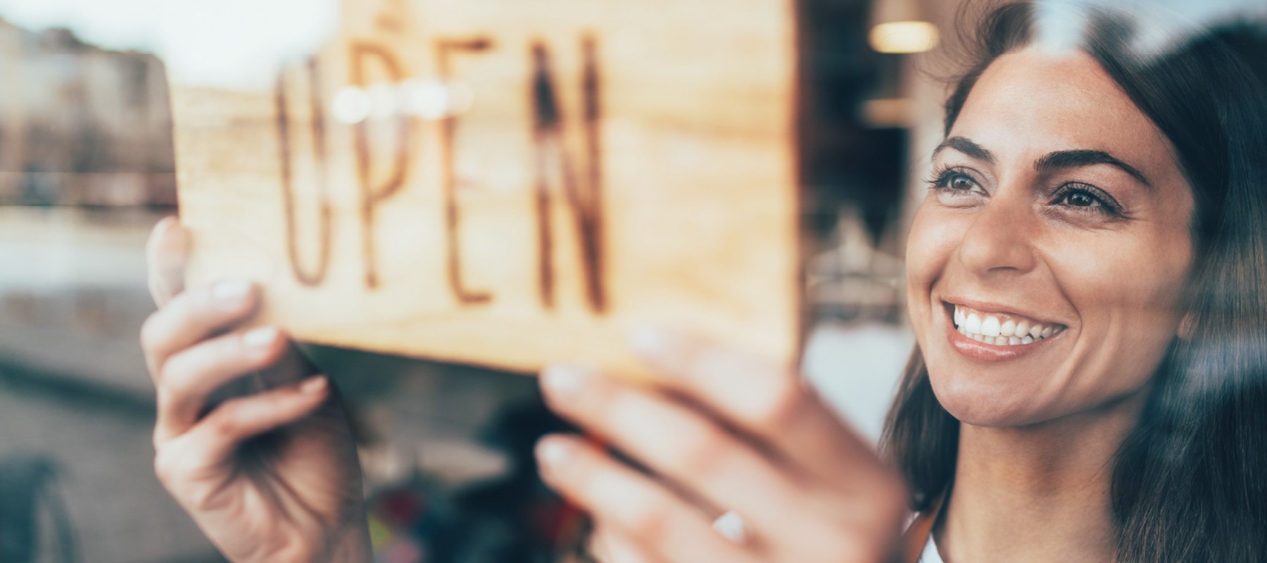 Woman turning an open sign at a storefront