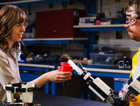 Amii roboticist works with a client with a robotic arm