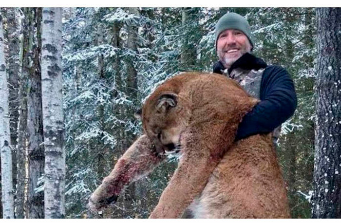 Man holding a cougar that he hunted