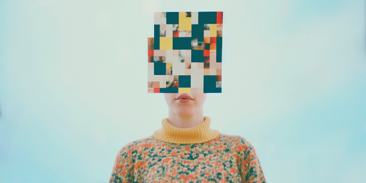 Person wearing a colourful patterned sweater with a high yellow turtleneck, standing against a pale blue background. Their face is obscured by a square collage of pixelated and blurred images in a mosaic style, featuring various colours and partial visuals.