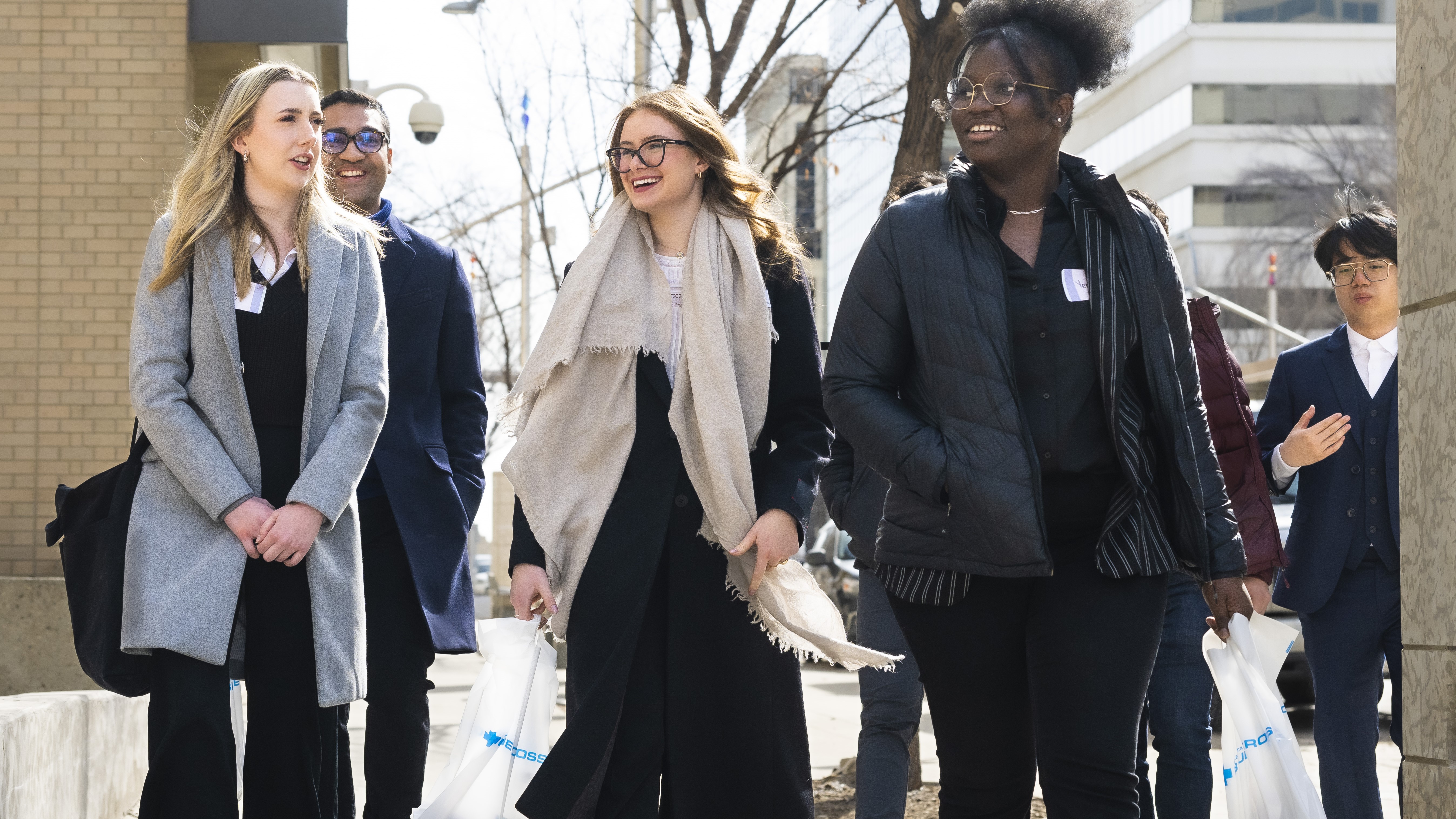 an image of a group of young women huddled together, laughing and smiling outside. 