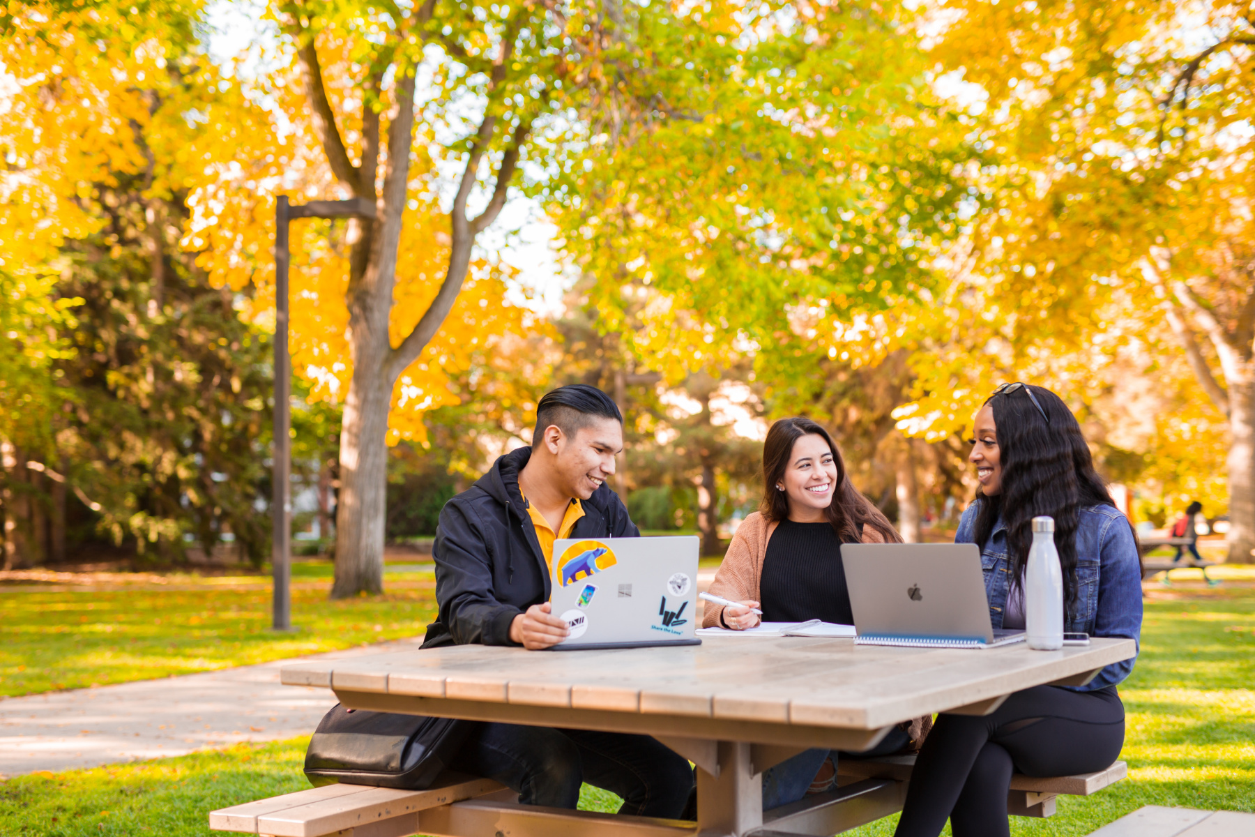 Students gathered outdoors in front of fall foliage