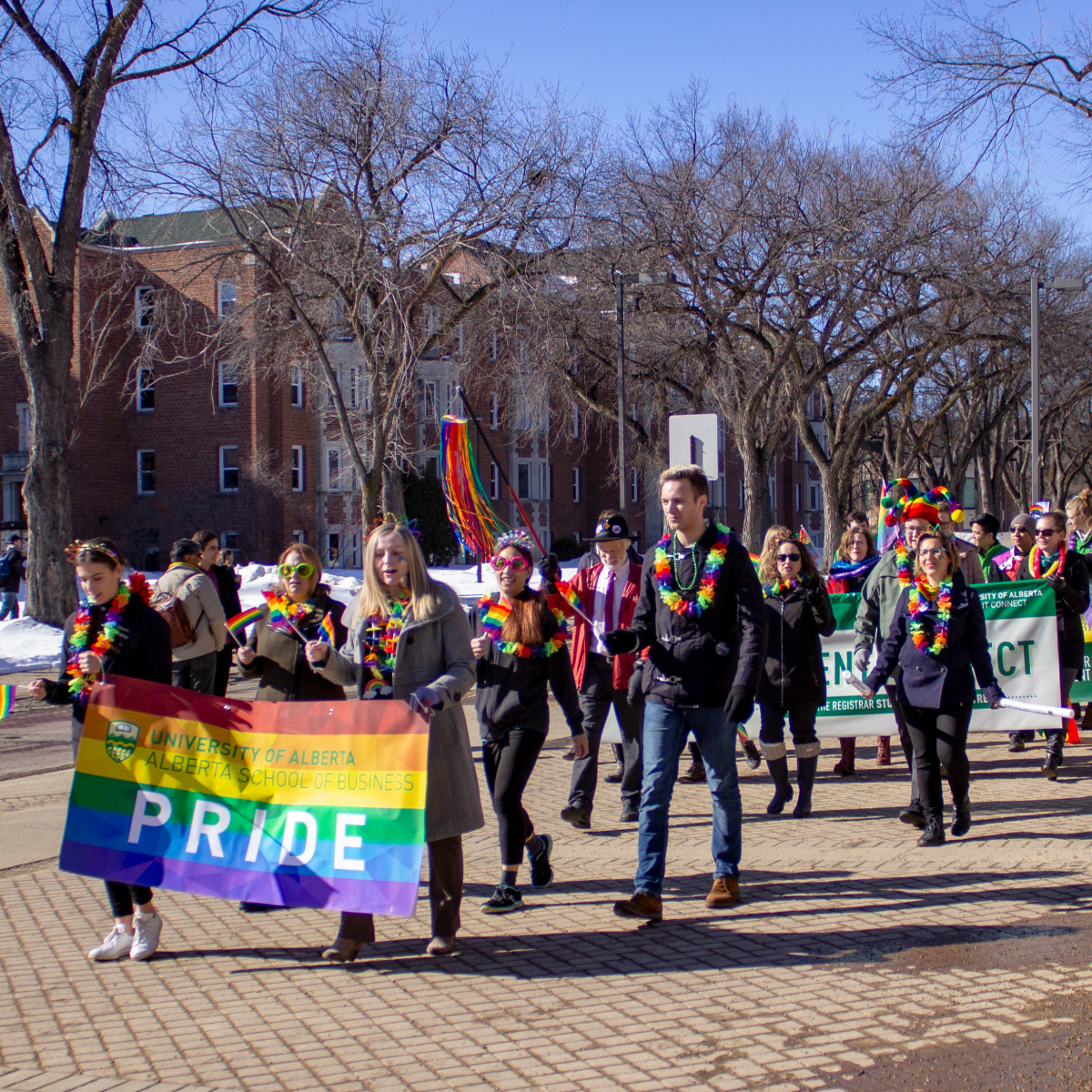 Pride parade with group wearing rainbow leis and hats and flags