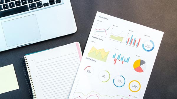 laptop and report with charts on desk