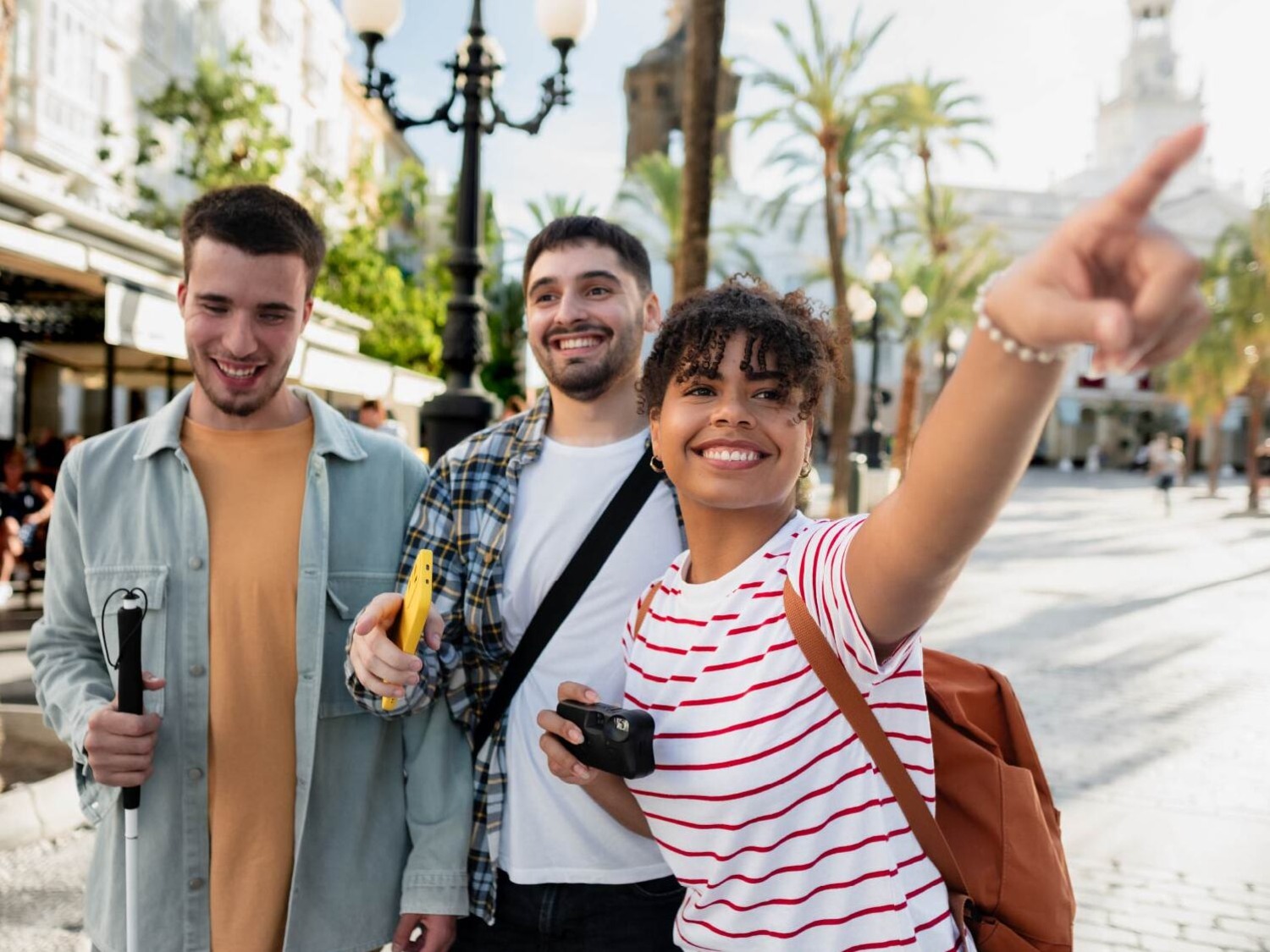 A diverse trio of students in sunlight on a sidewalk.