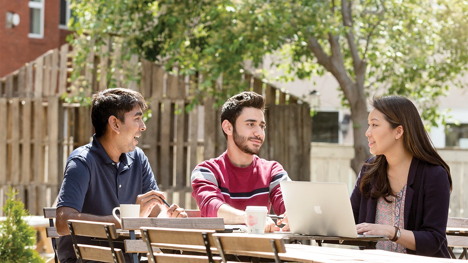 Students sitting at a picnic table outside