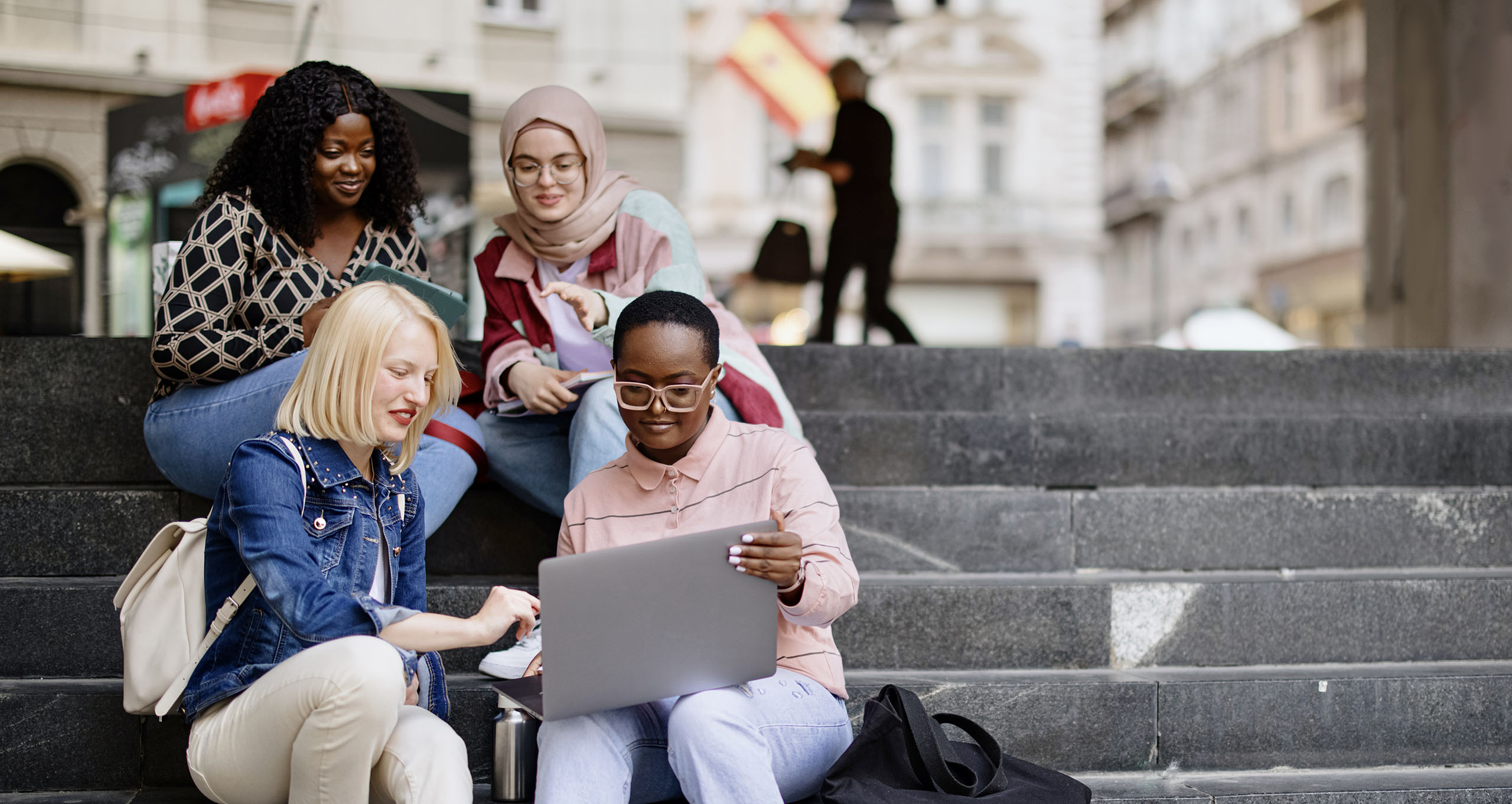 Students sitting on stairs and looking at a laptop