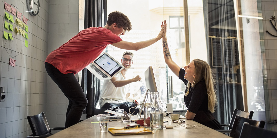 Three students celebrating and high-fiving