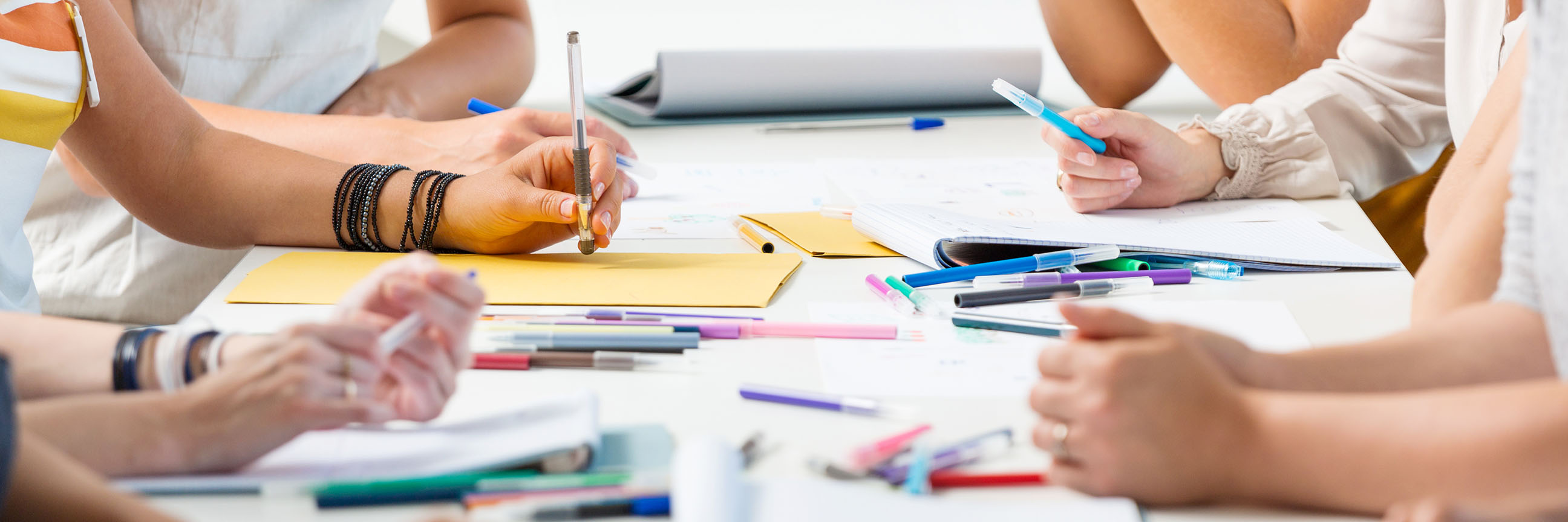 People writing with coloured pens at a table