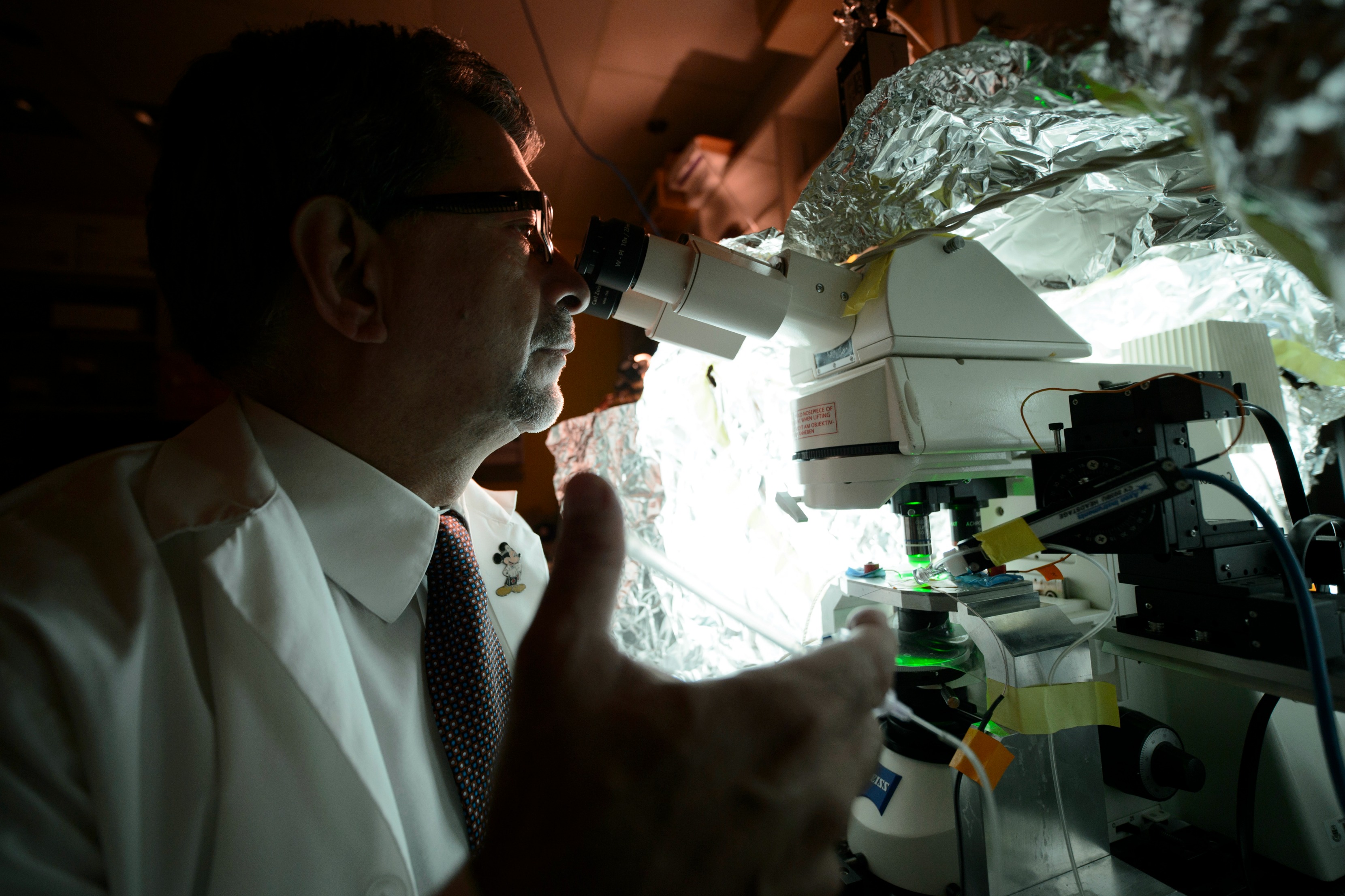 Jack Jhamandas working with a microscope in a University of Alberta lab