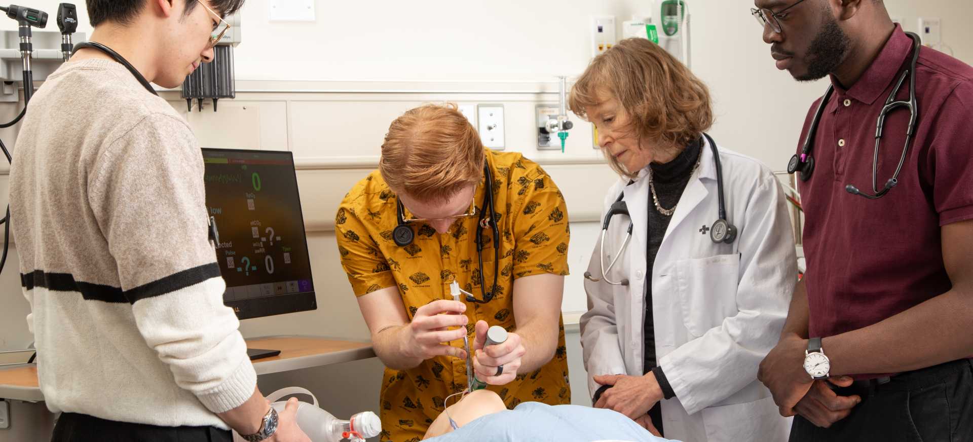 Four people working on a medical dummy