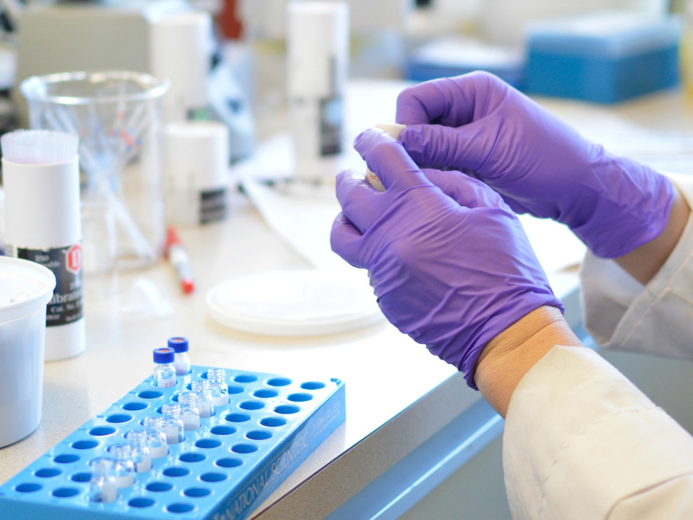 A researcher handles test tubes in a lab environment.