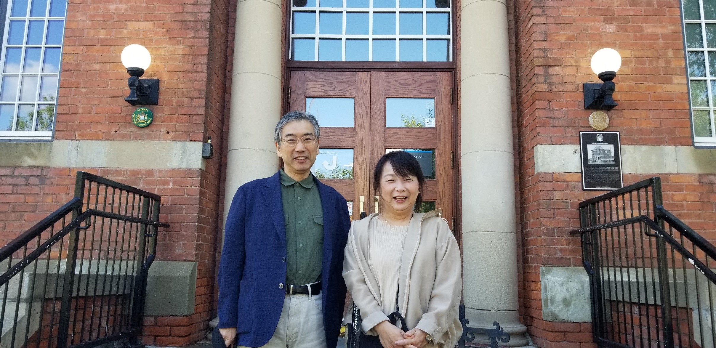 Two people posing in front of a building