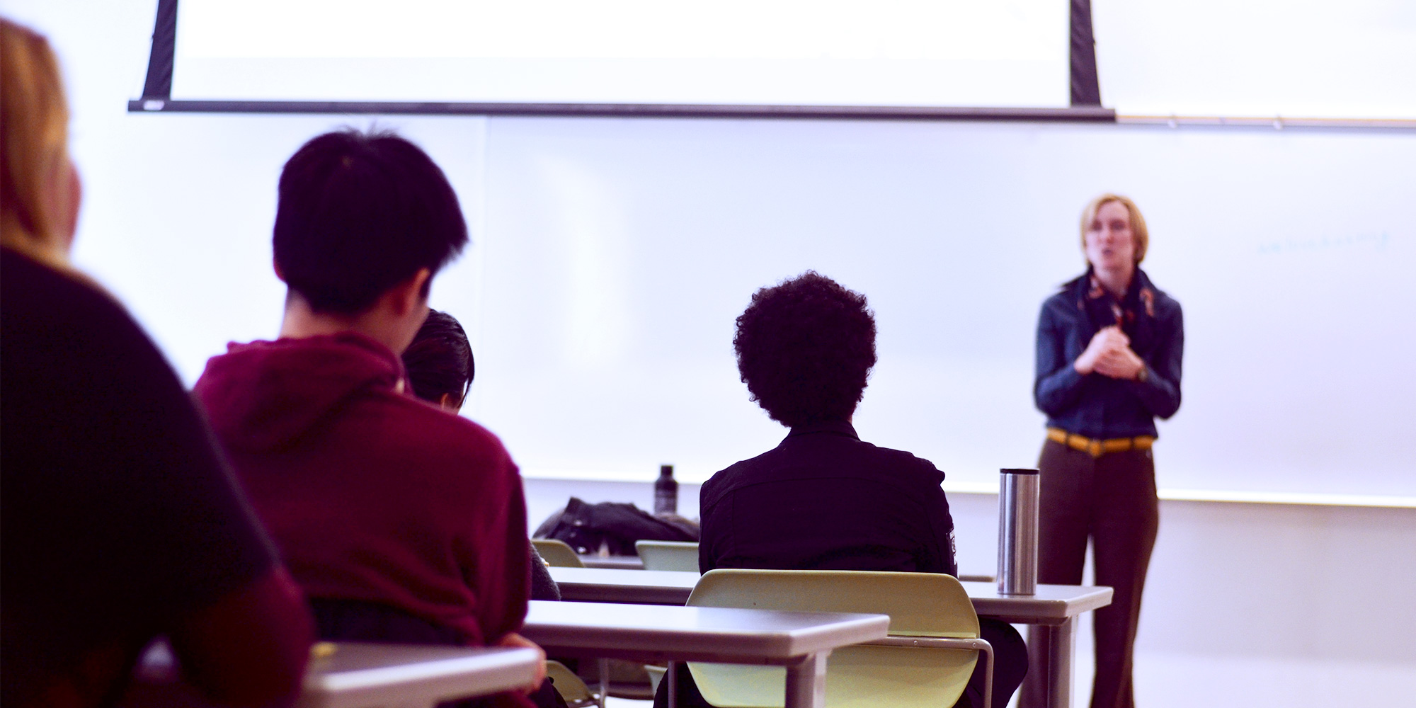 Young people facing front of classroom, instructor addressing class.