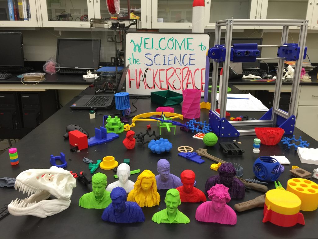 3D printed sculptures on a desk with a sign saying "Welcome to the Science Hackerspace"
